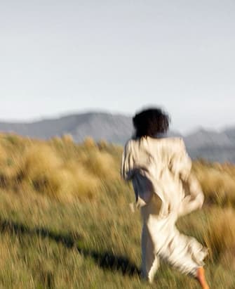 A woman walking through open grassland